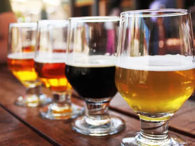 Four different beers in a flight for tasting on a bar top.