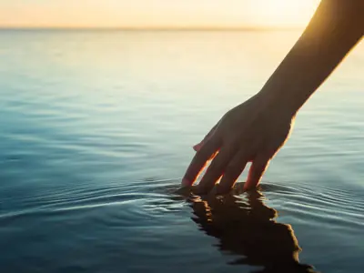 Fingertips dipping in a lake