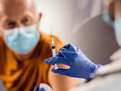 Gloved hand holding vaccine needle