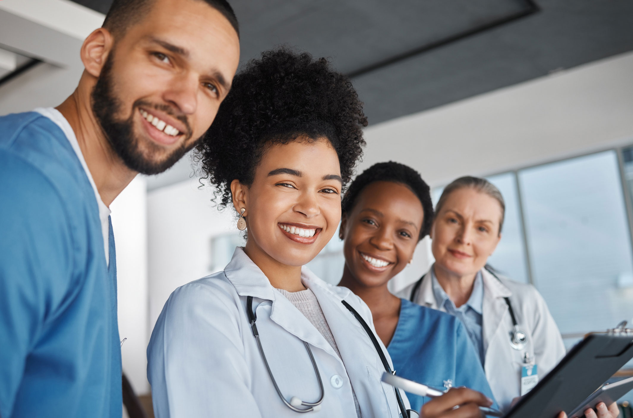 Group of four health care providers smiling at camera in a clinic.