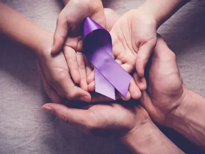 Hands holding purple awareness ribbon