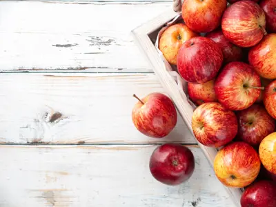 Box of apples sitting on a white table.