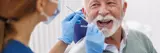 Dental hygienist checking the teeth of a smiling elderly man in a dental office. 